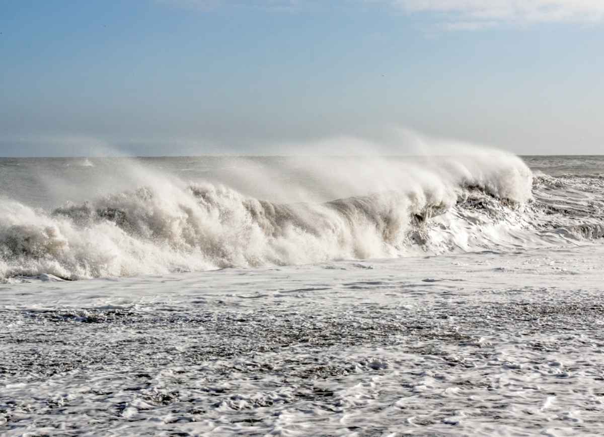 Powerful ocean waves crashing onto a black sand beach on a windy winter day in Iceland.