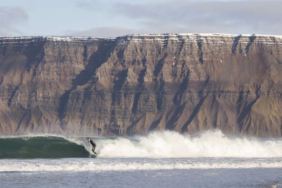 Man surfing in Iceland by the impressive fjords 