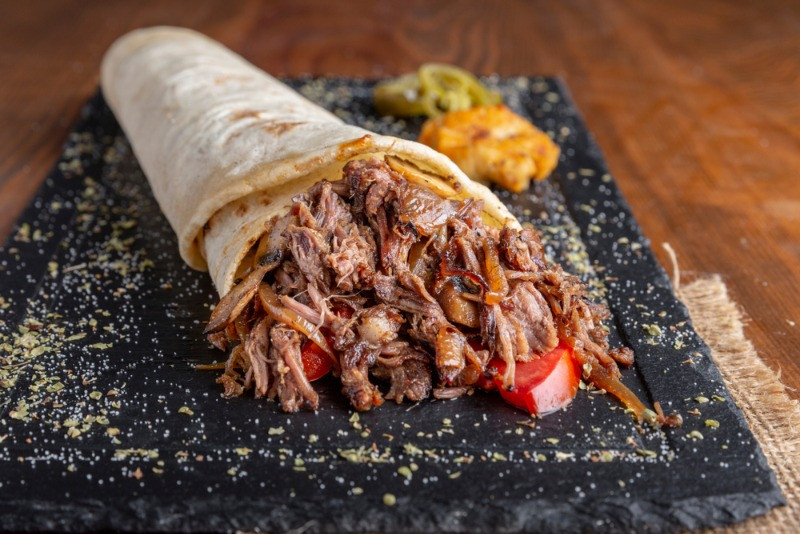 pulled lamb wrap served on a stone plate