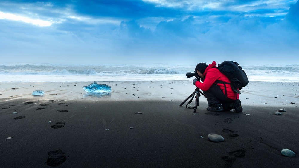 Photographer taking a shot of a beautiful black sand beach in Iceland
