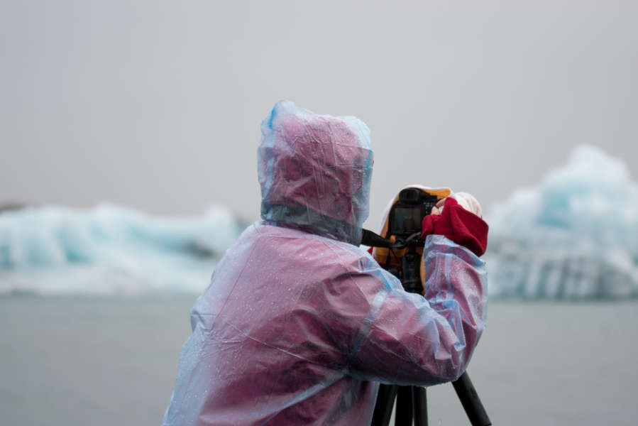photographer wearing a raincoat and protecting his equipment in a photo tour