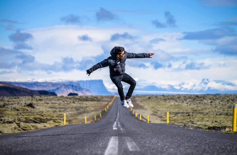 young man jumping in the middle of an Icelandic road
