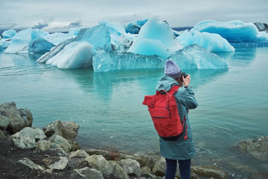 Young woman taking a picture of the icebergs at Jokulsarlon glacier lagoon