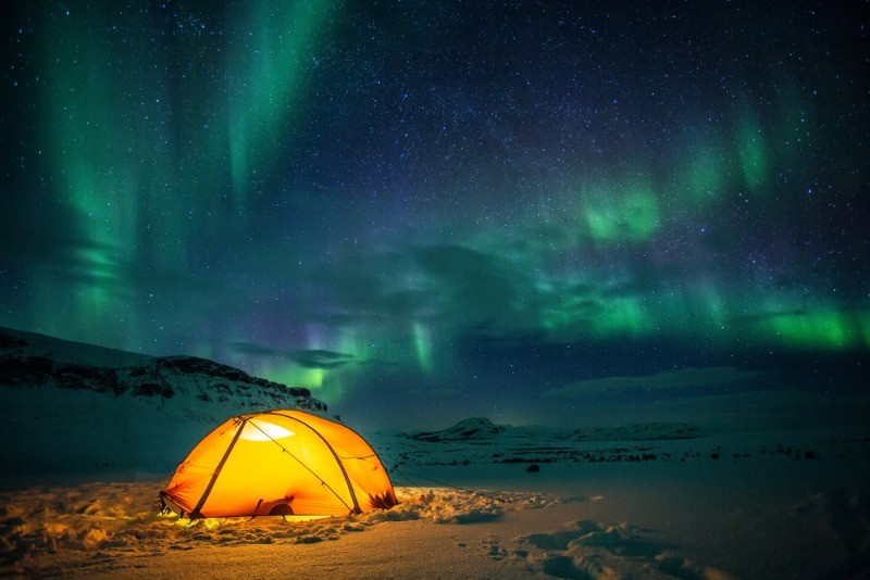 Tent set on snow and under the northern lights