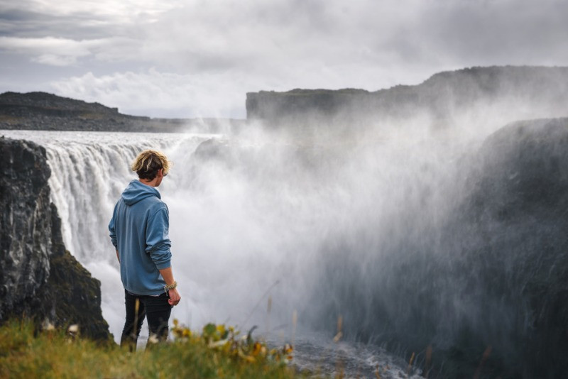 Young man overlooking the Dettifoss waterfall in Icelands diamond circle