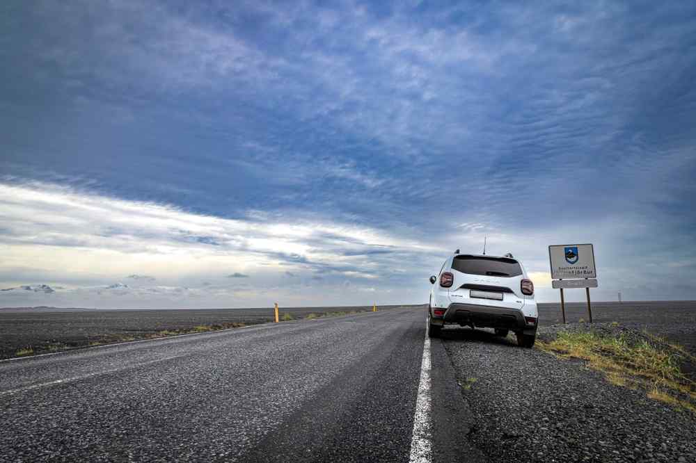 Dacia Duster on Iceland's Ring Road White SUV parked beside an Icelandic road under a cloudy sky.