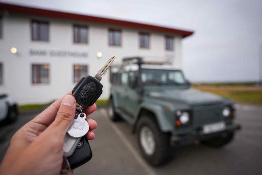 Renting a premium 4x4 in Iceland Hand holding car keys in front of a parked 4x4 rental vehicle in Iceland.