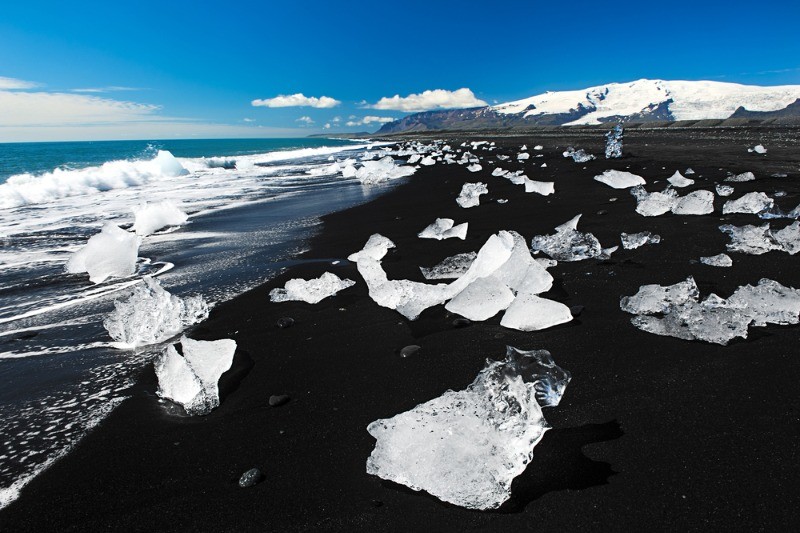Ice pieces scattered on a black sand beach