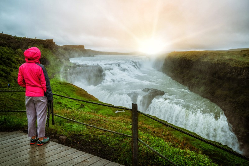woman enjoying rainy Iceland by a waterfall