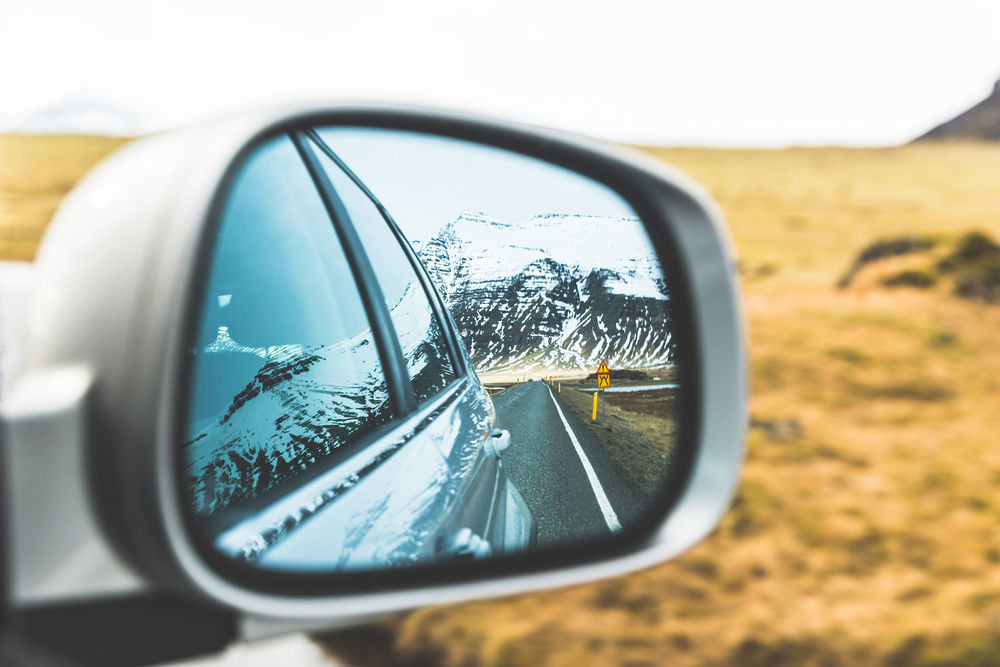Picture of a mountain ridge reflecting on a cars rear view mirror