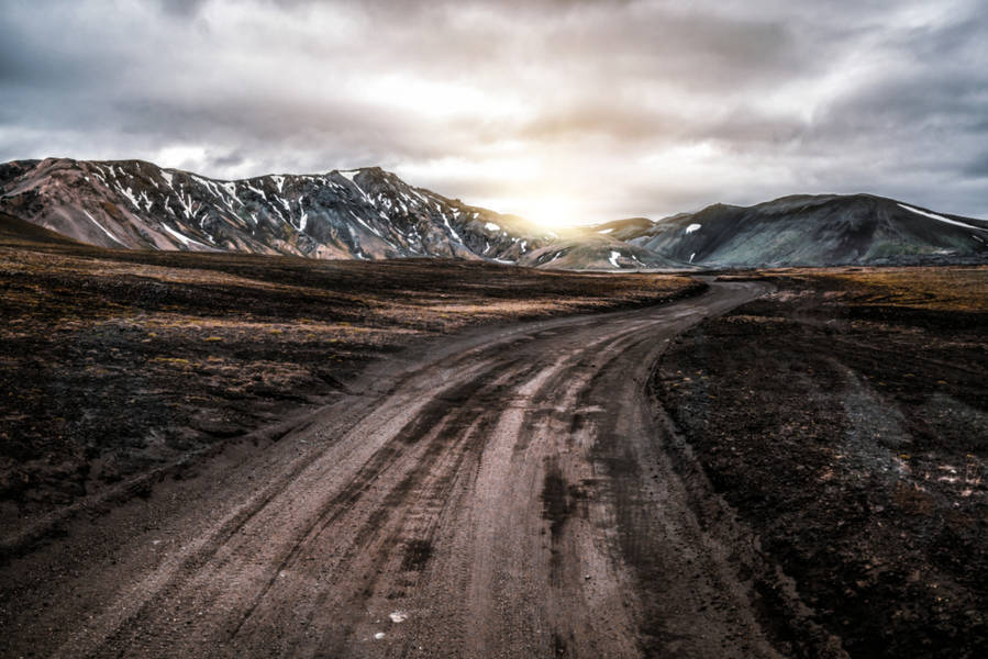 Unpaved gravel road in Iceland with mountains on the background