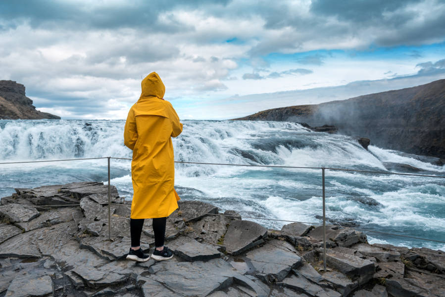 Girl in a yellow raincoat enjoying the views of Gullfoss waterfall