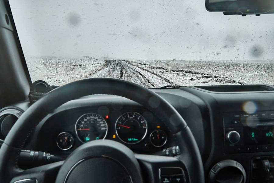 steering wheel of a car with a snowy road ahead