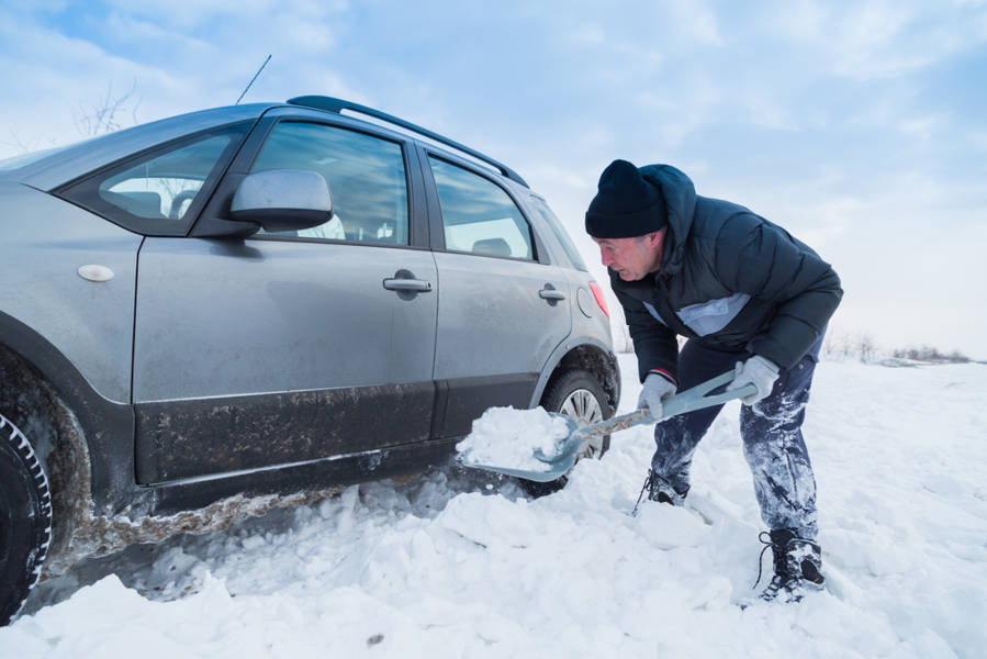 men shoveling snow out to get his car moving again