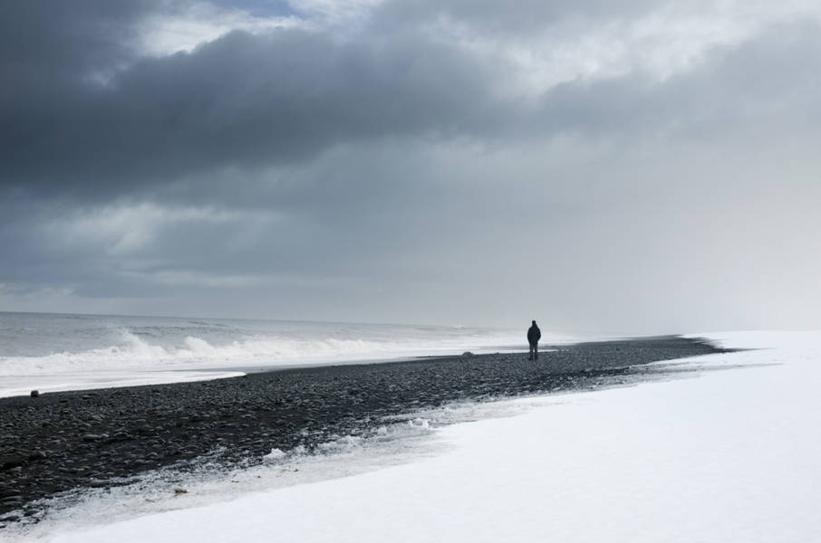 A man walking by one of the least visited beaches of Iceland