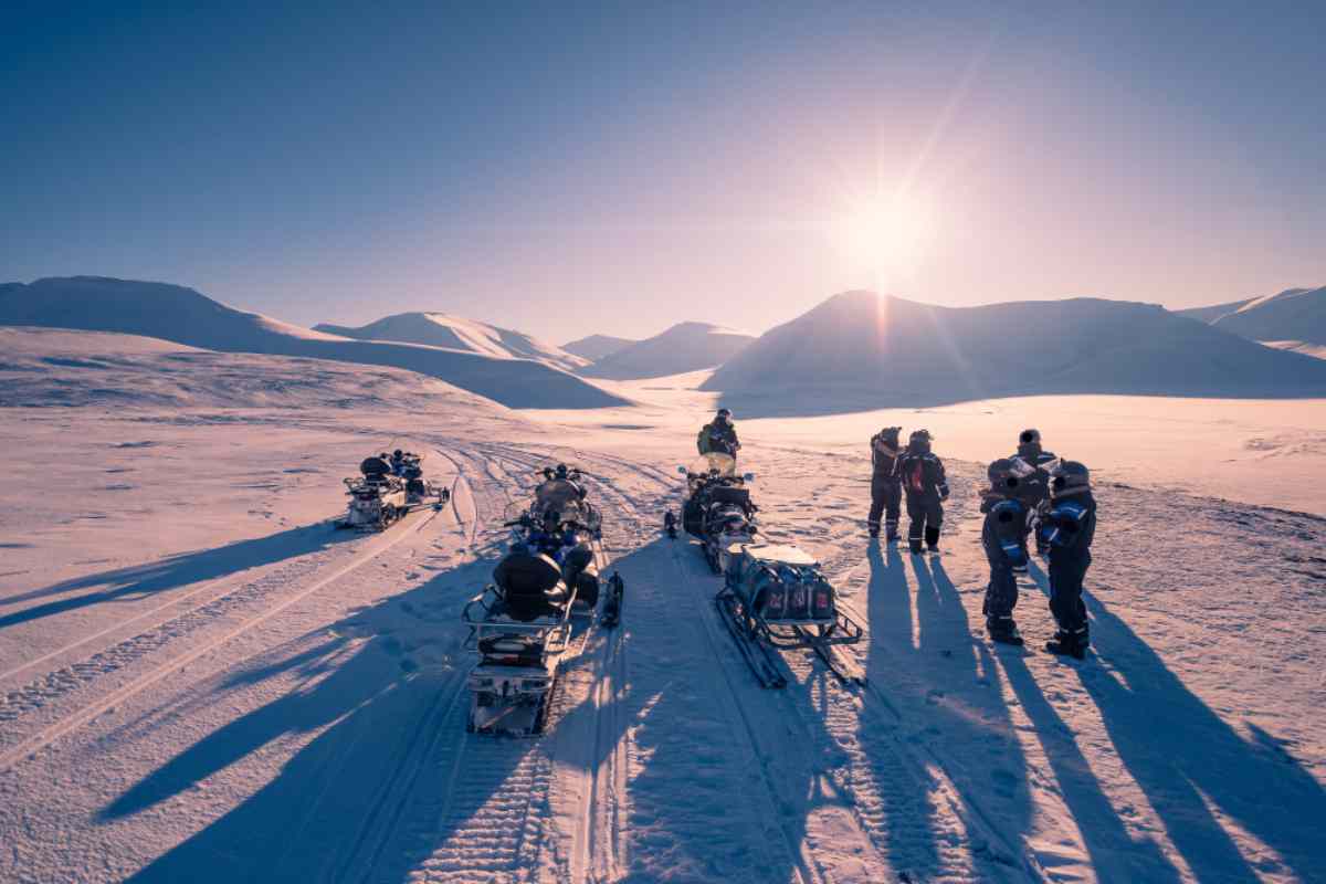 Group of visitors heading on a snowmobile tour at dusk