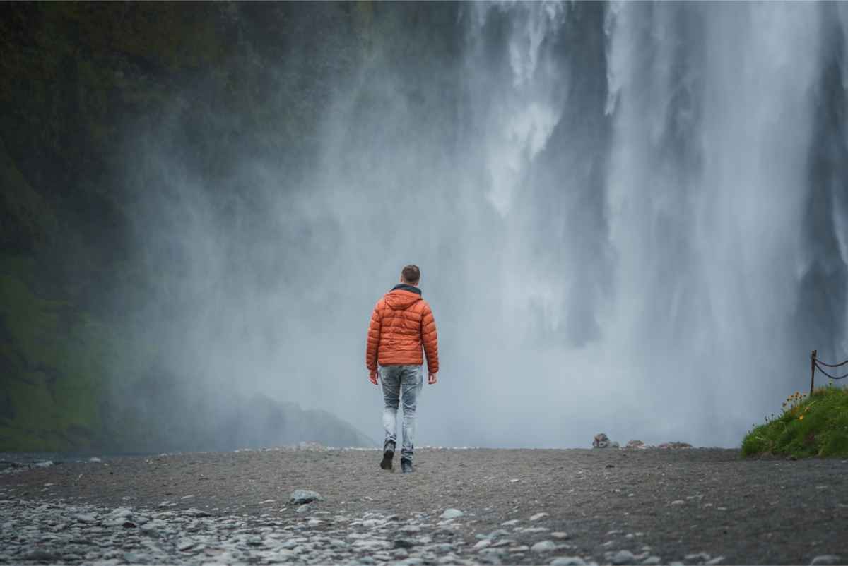 Tourist wearing jeans near a waterfall splashing water