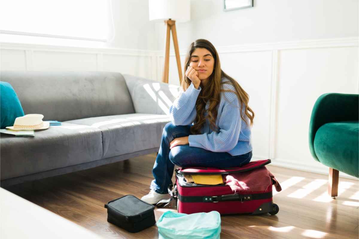 Woman sitting on her suitcase hoping it will closer