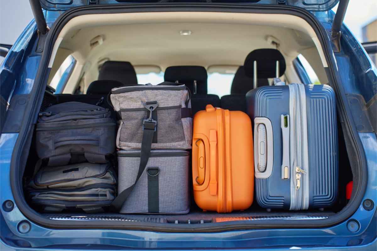 Trunk of a car filled up with suitcases and backpacks