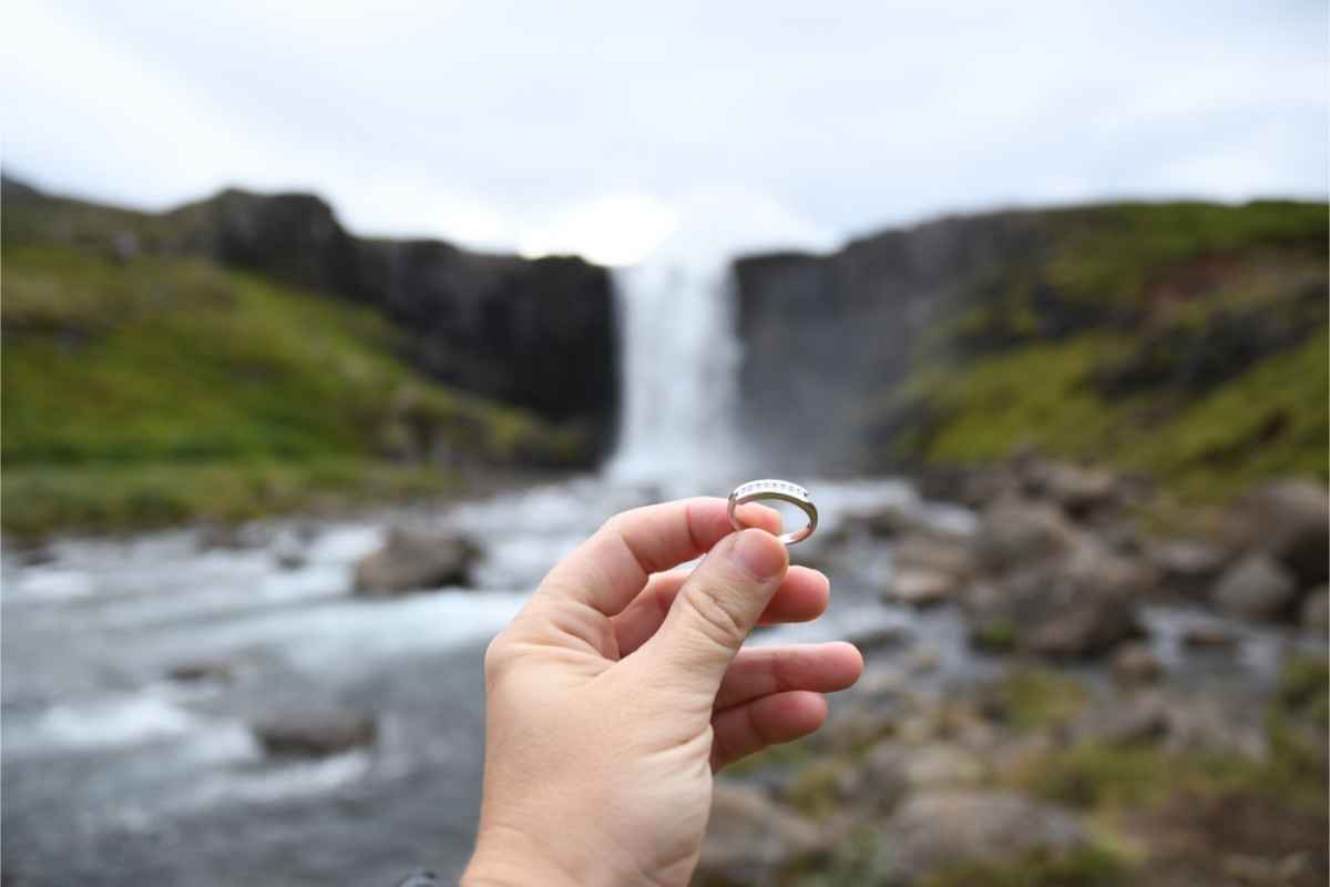 Man holding a wedding ring in front of a waterfall in Iceland