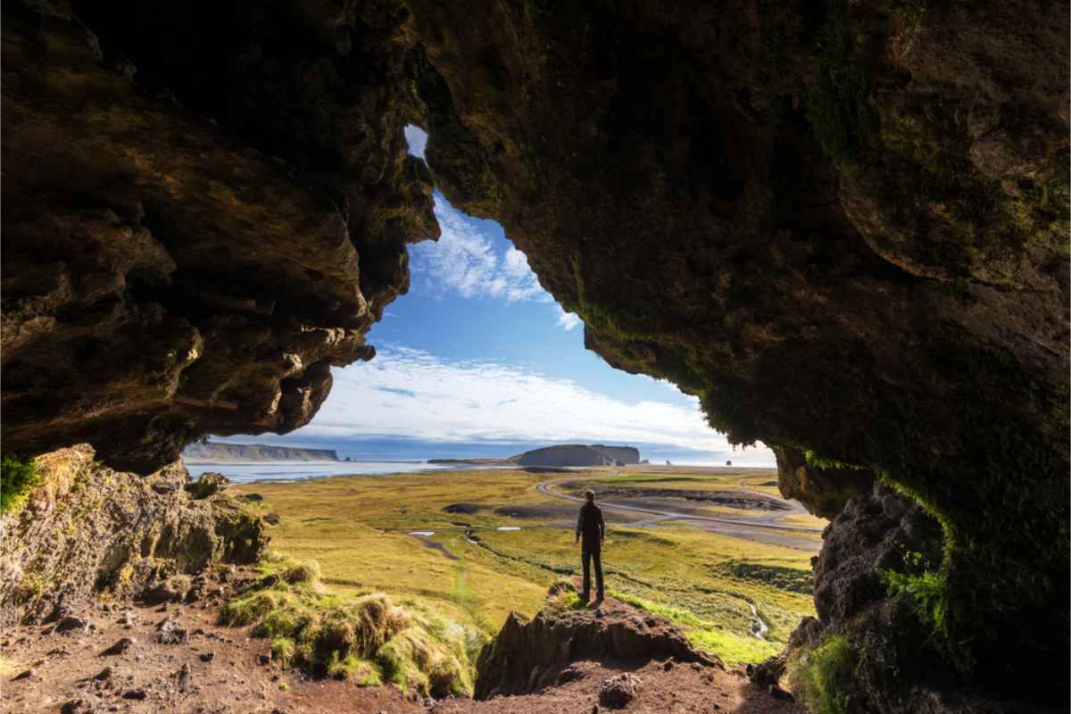 Tourist standing at the opening of Loftsalahellir cave