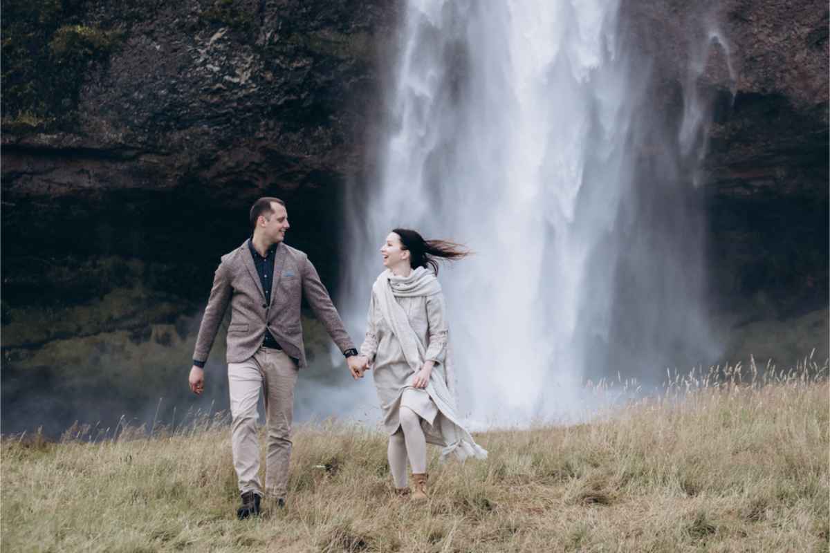 Couple holding hands by a waterfall in Iceland