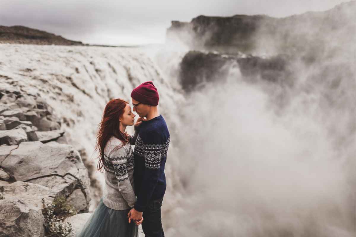 Couple standing by Detifoss in a romantic posture