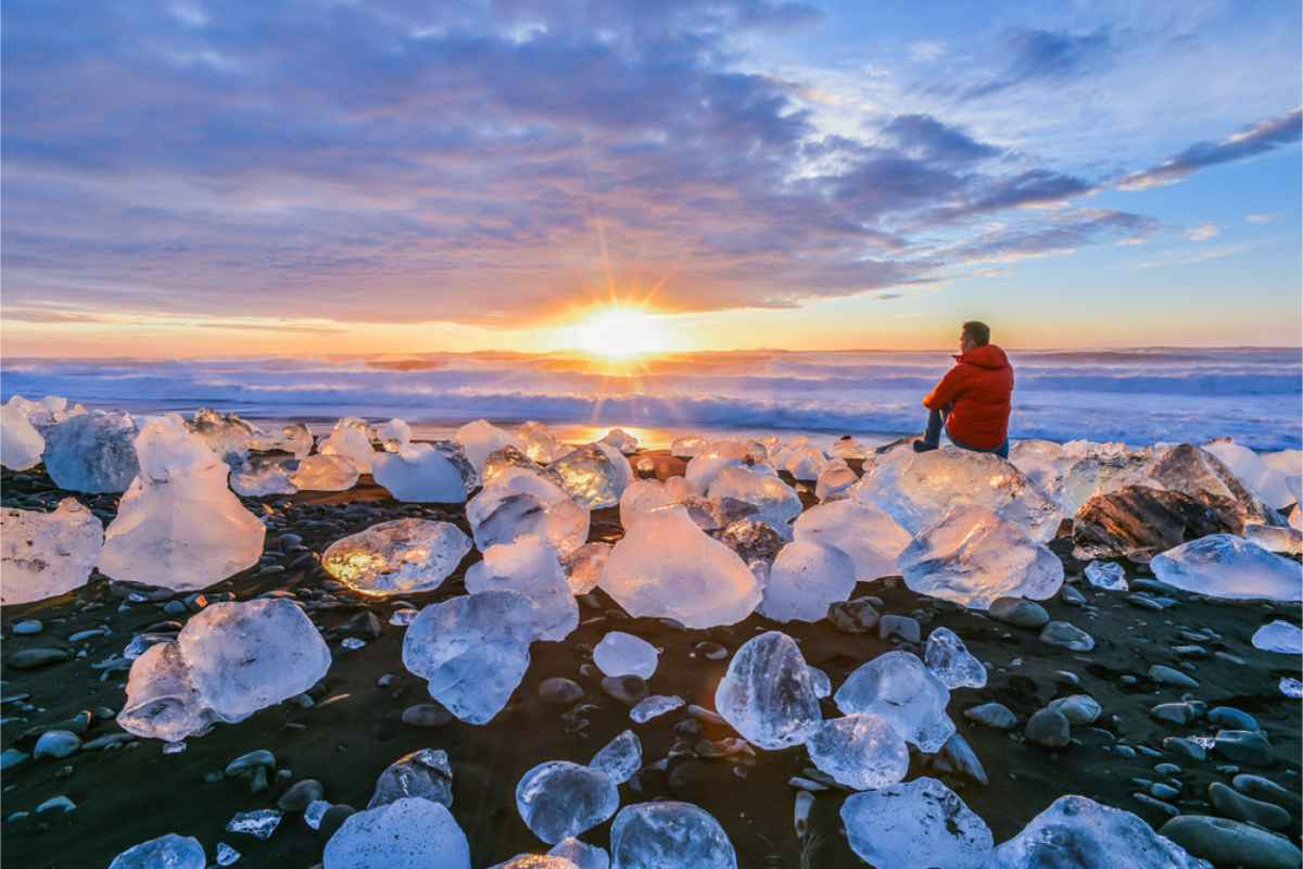 Man sitting on an Iceberg at Diamond beach at Dusk