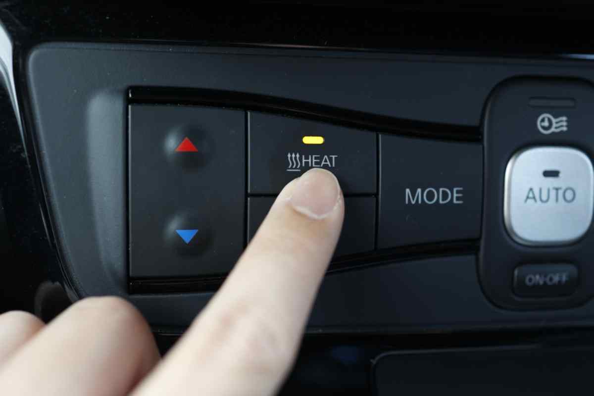 The importance of having a heated vehicle in Iceland Finger pressing the heat button on a car dashboard for winter driving comfort.