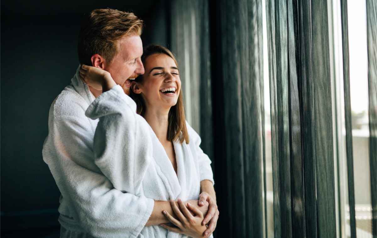 Happy couple in their bathrobes enjoying a relaxing evening in their hotel