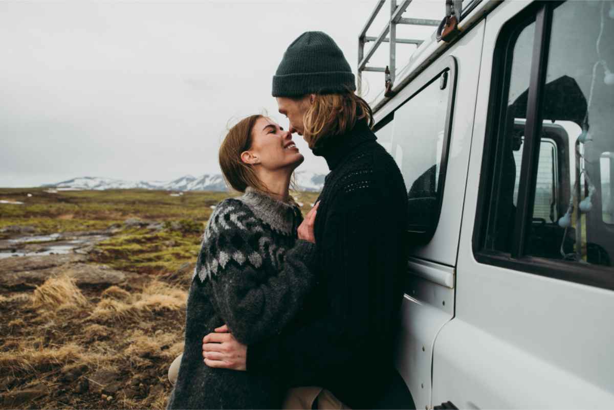 Couple about to kiss while parked by a lava field in Iceland