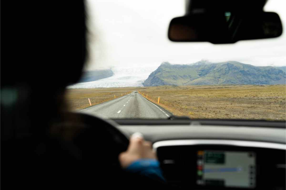 man driving in Iceland´s ring road with a glacier in the background