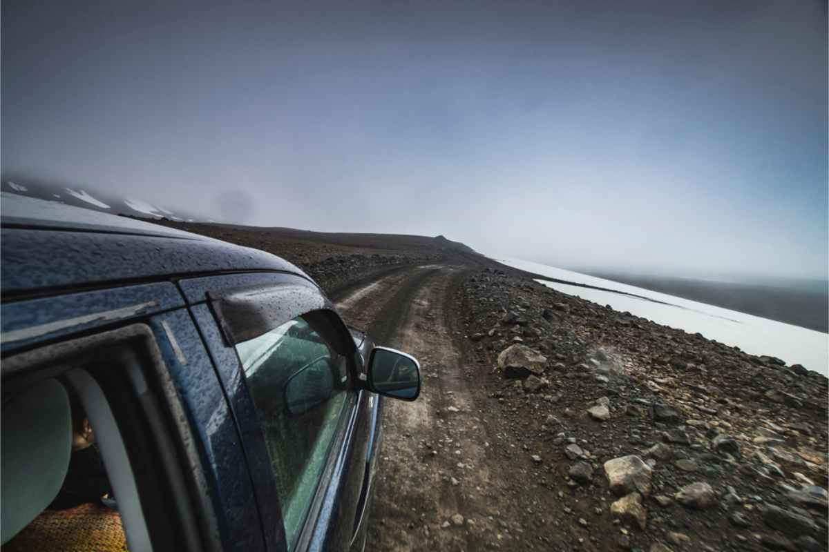 4x4 vehicle driving a gravel road in Iceland on a cloudy day