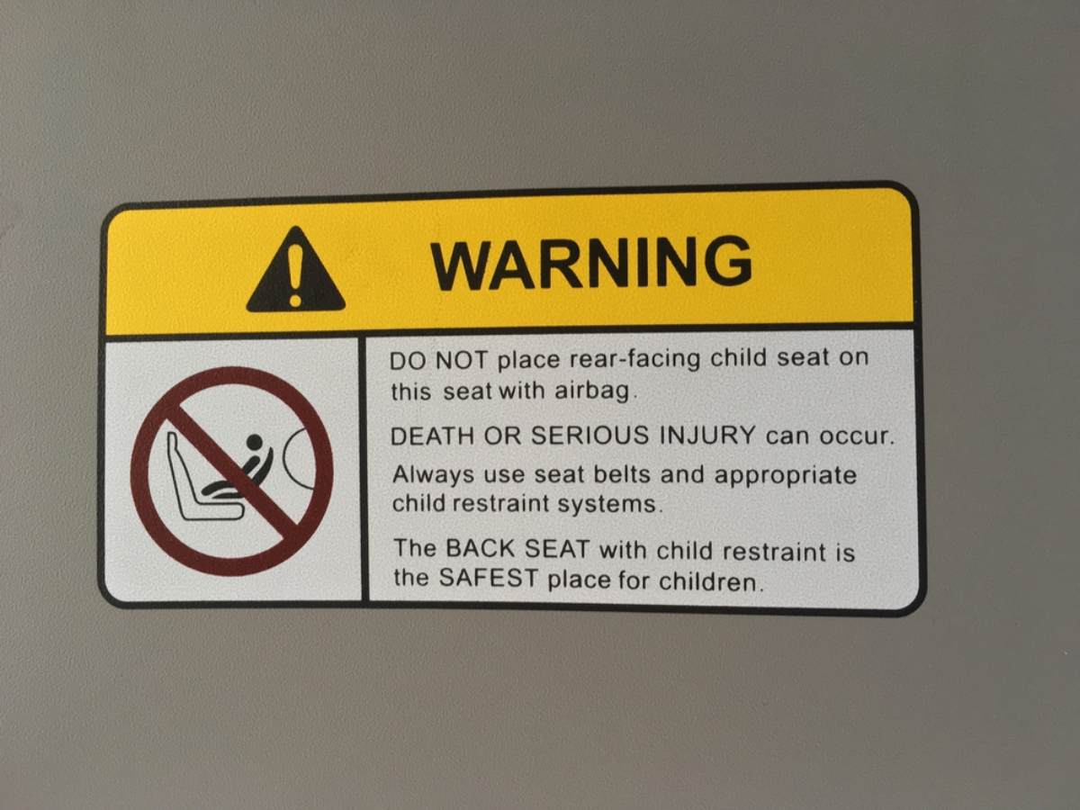Kann ein Kind in Island auf dem Vordersitz mitfahren? Warnschild mit einigen Dingen, die man bei Kindersitzen nicht tun sollte
