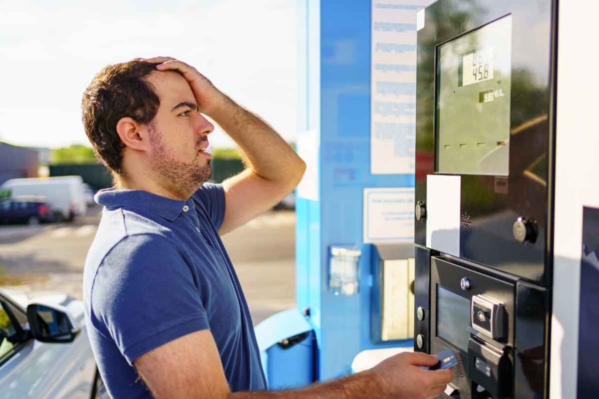 Ein Mann befindet sich an einer Tankstelle, w&auml;hrend er tankt und den Benzinpreis &uuml;berpr&uuml;ft.