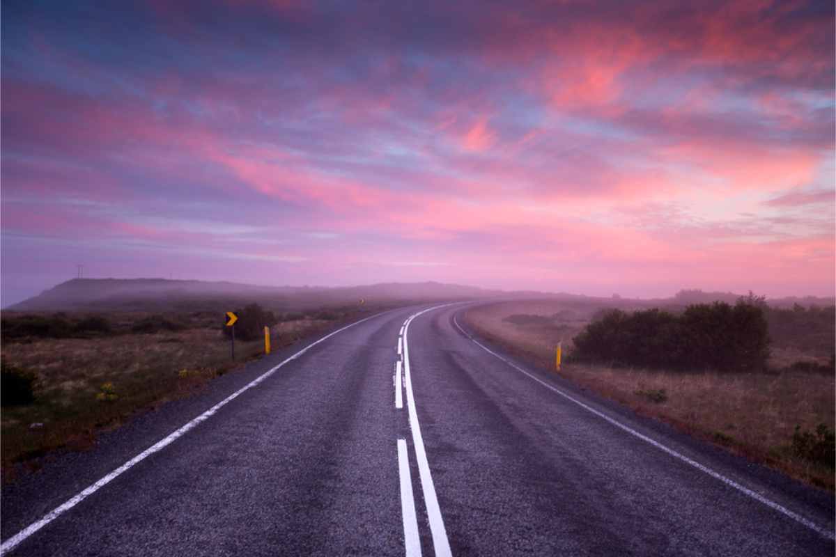 Offene Straße in Island mit einem wunderschönen Himmel in Rosa- und Lilatönen.