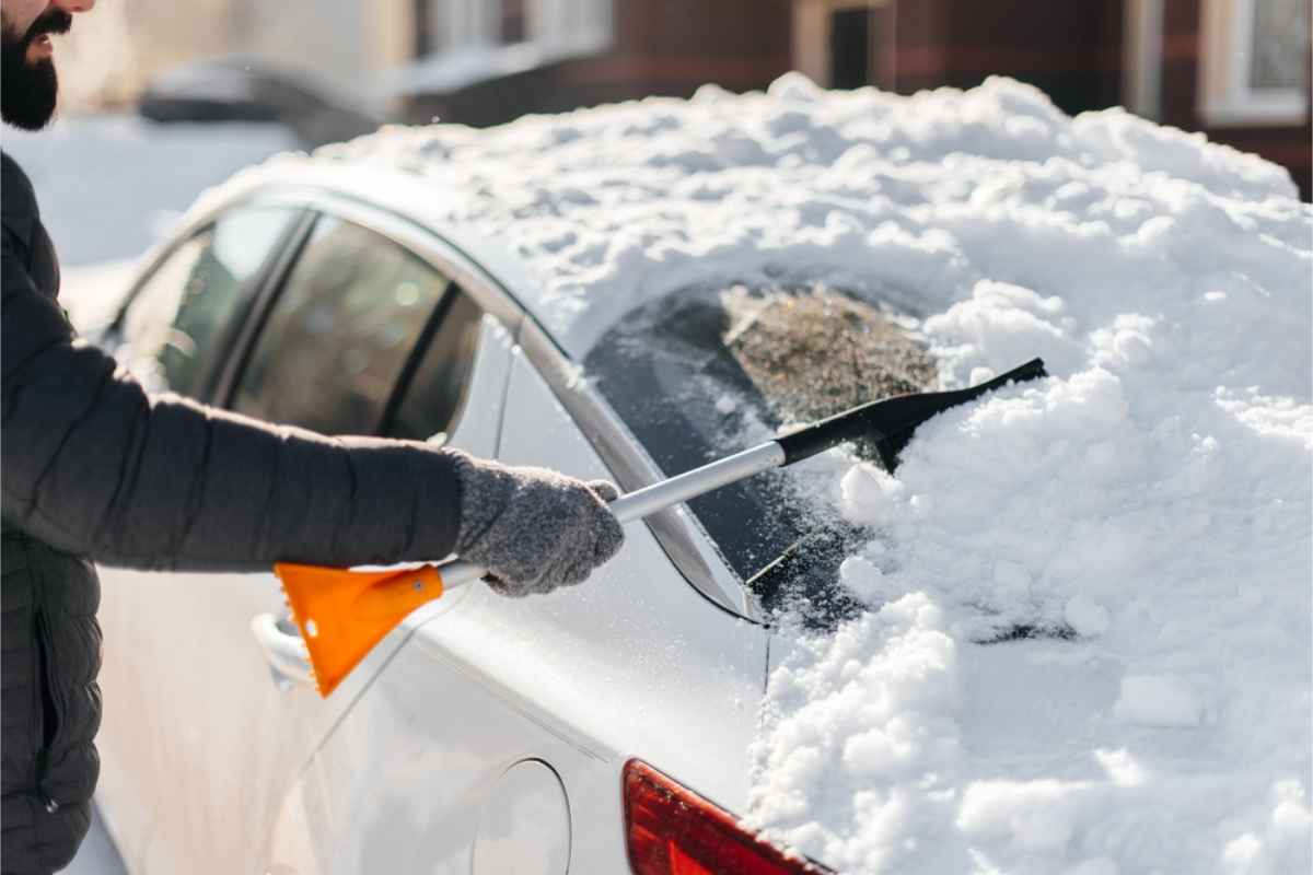 Nützliches Zubehör für einen Winter-Autotrip Tourist kratzt Schnee von seinem Mietwagen