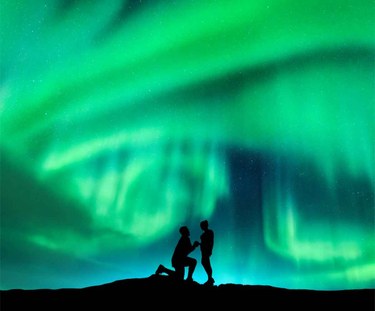 Mann macht seiner Freundin unter den Nordlichtern in Island einen Heiratsantrag