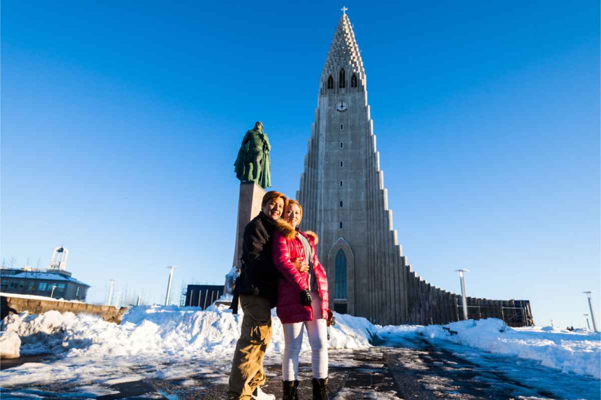 Asiatisches Paar umarmt sich und posiert vor der Hauptkirche von Reykjavik