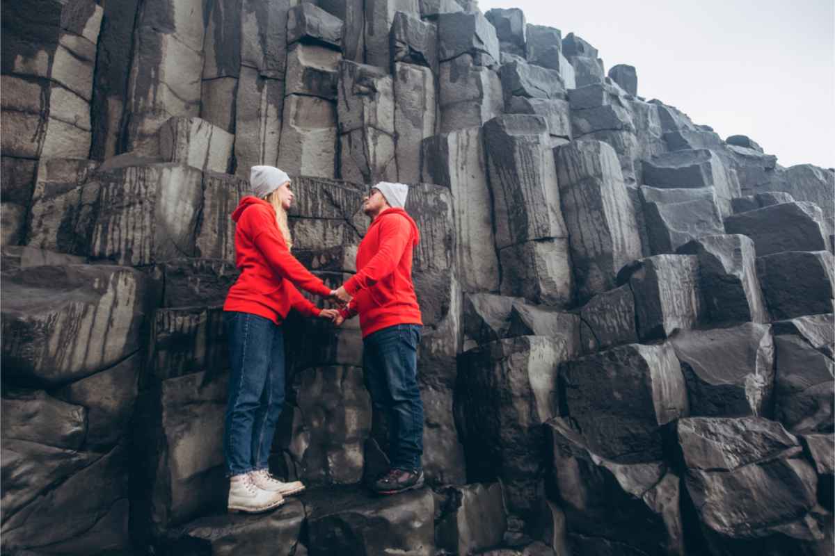 Paar steht auf den Basaltsäulen von Reynisfjara