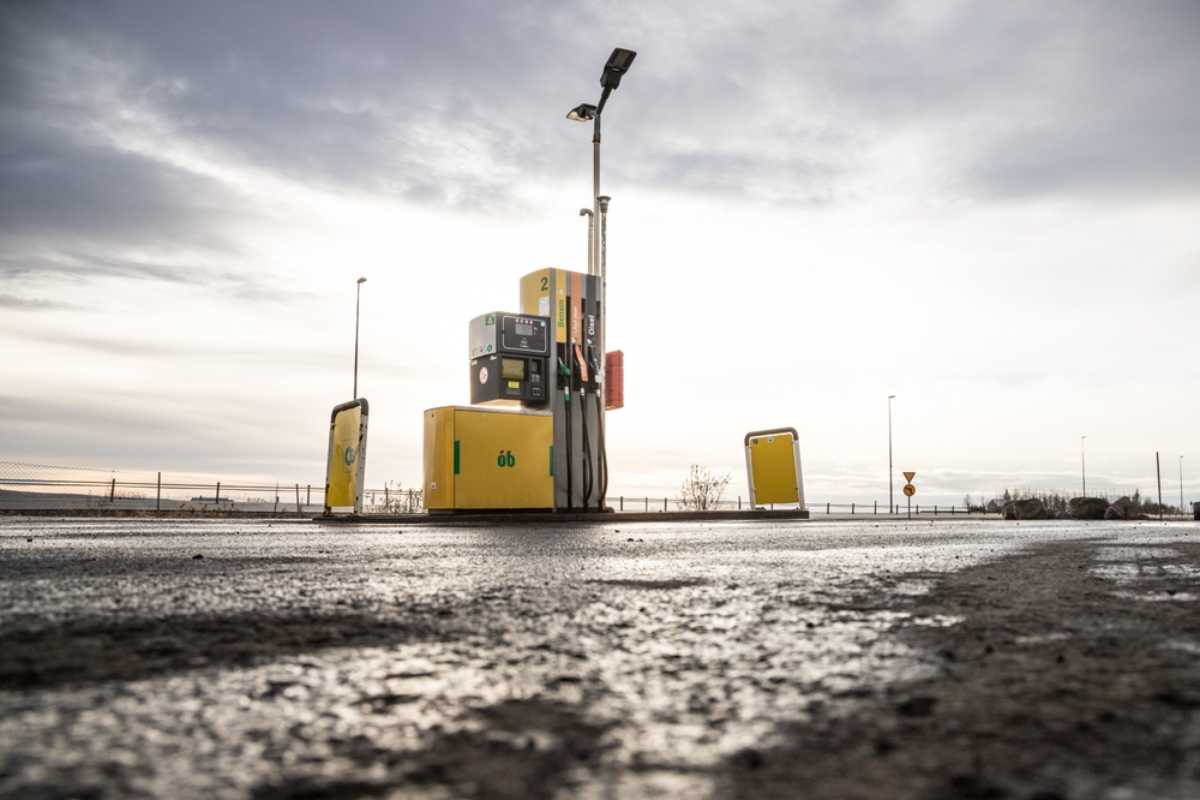 Dónde encontrar estaciones de servicio en Islandia Surtidor en una estación de servicio islandesa junto a una carretera mojada bajo un cielo cubierto