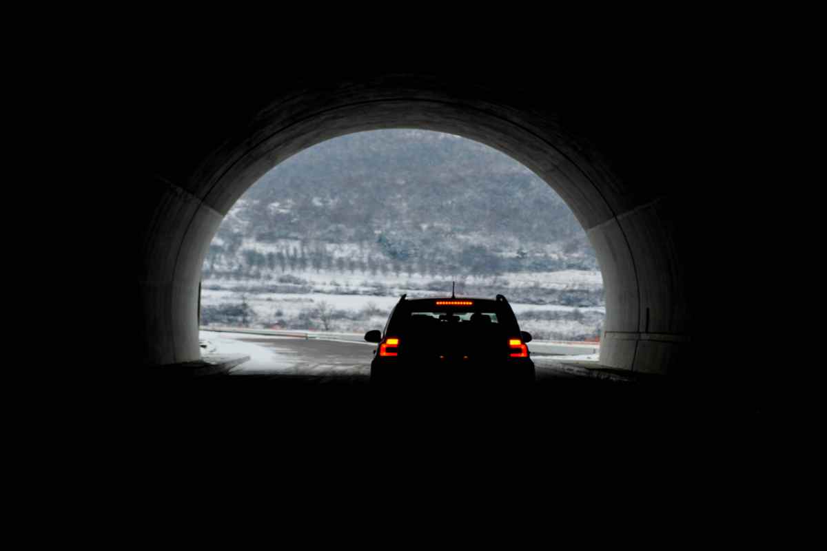 Túneles de un solo carril en Islandia Silueta de un coche saliendo de un túnel en Islandia con un paisaje nevado al frente