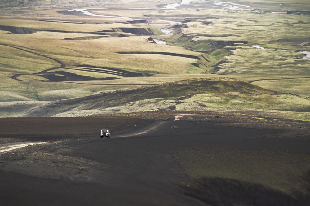 Highlands de Islandia y estaciones de carga para vehículos eléctricos Coche conduciendo por una carretera ondulada en Highlands de Islandia