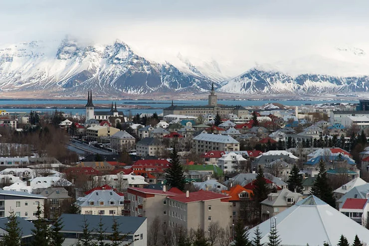 Vista panorámica de Reikiavik, Islandia, con casas coloridas y edificios históricos, y el monte Esja nevado al fondo