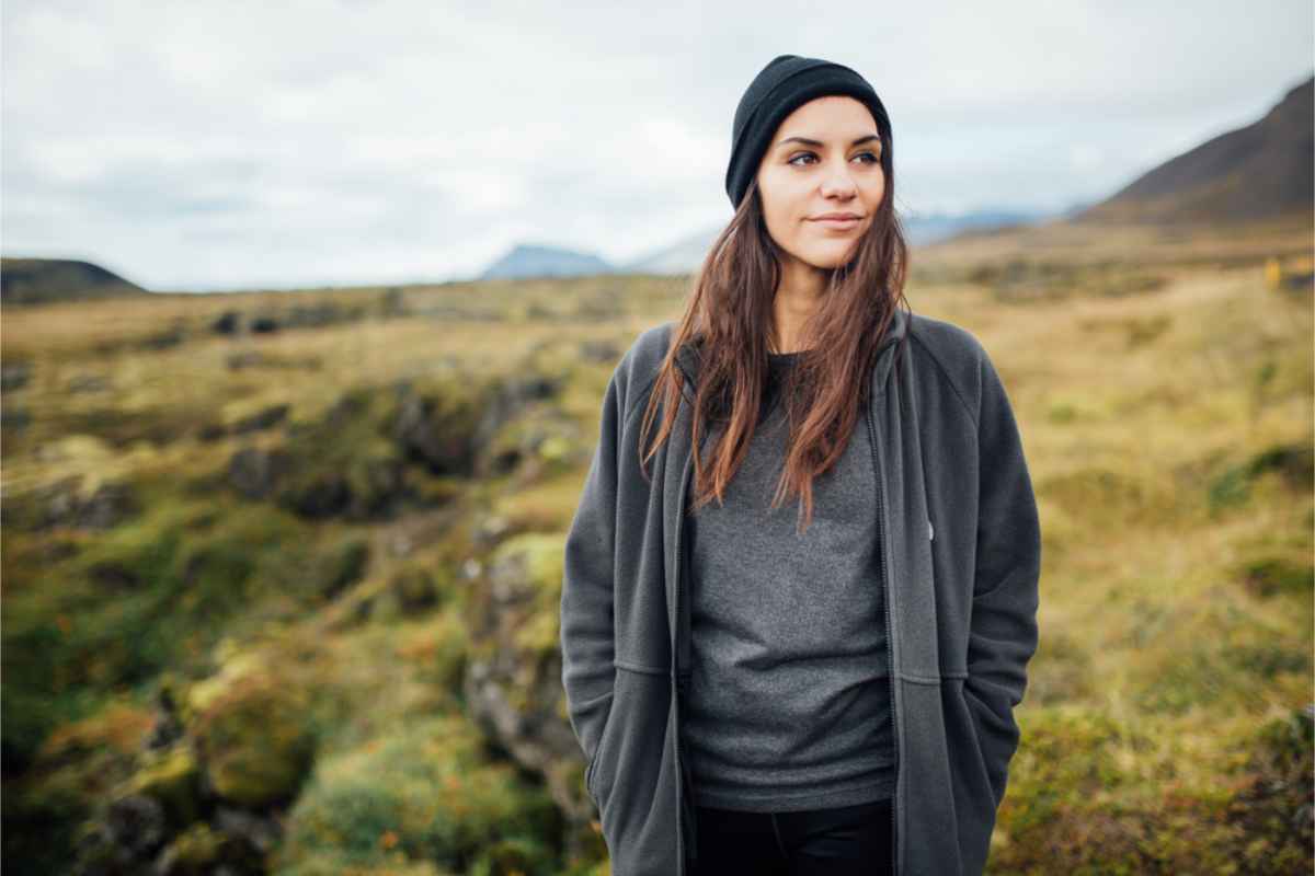 Joven vestida cómodamente con un gorro y ropa casual pero impermeable.