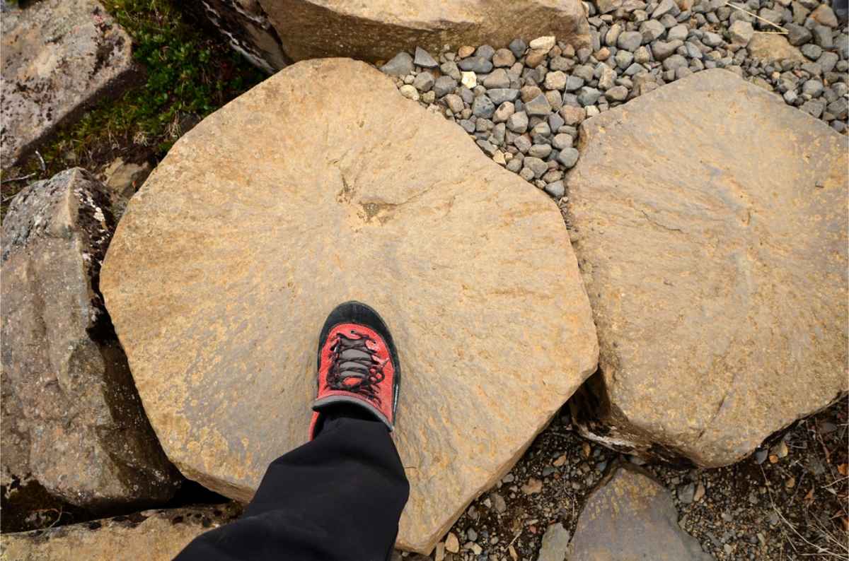 Consejos de calzado para agosto en Islandia Bota de senderismo negra y naranja encima de una roca