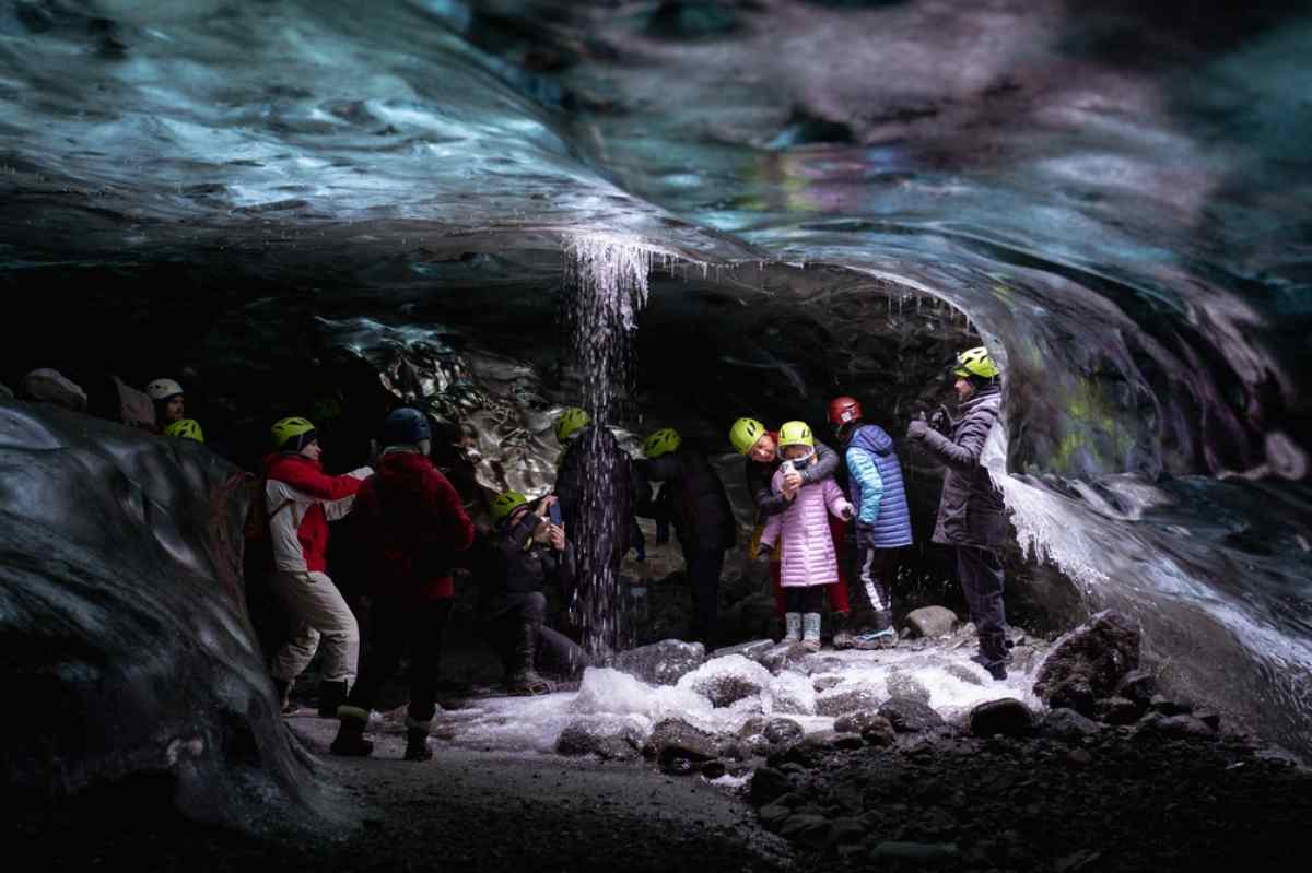 Grupo de turistas con casco explorando una cueva de hielo azul en Islandia.