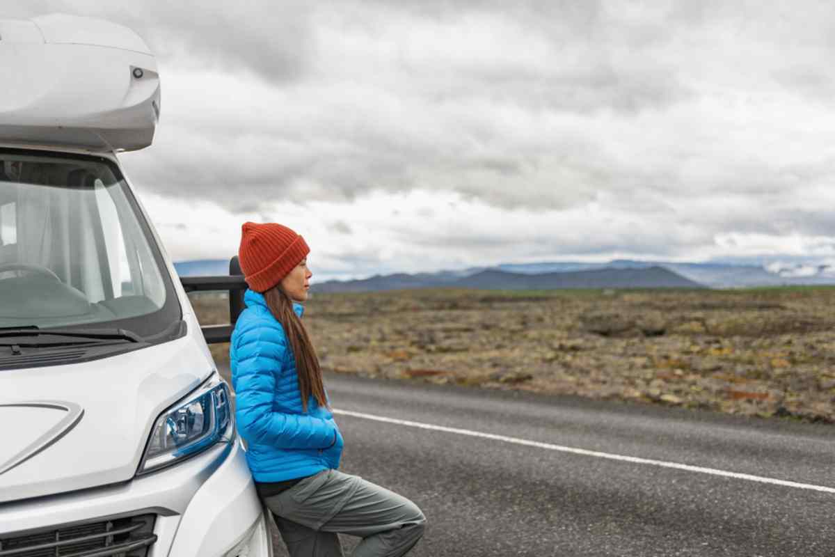 Viajero apoyado en una camper aparcada junto a la carretera en Islandia.