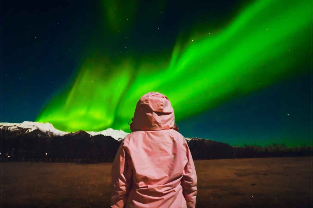 Turista disfrutando de las auroras boreales con la chaqueta adecuada para el frío