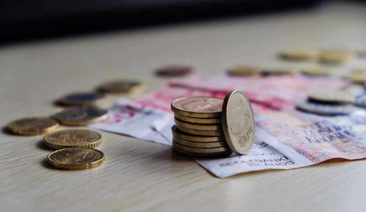 Monedas y billetes de corona islandesa sobre una mesa, con una pila de cambio junto a una moneda de 100 coronas.